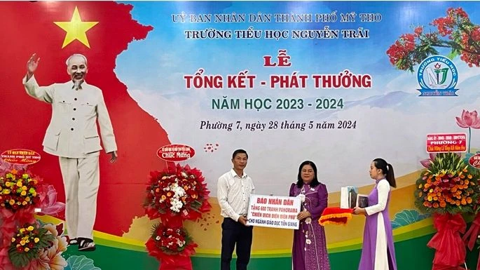 Phó Giám đốc Sở Giáo dục và Đào tạo tỉnh Tiền Giang Huỳnh Thị Phượng nhận bảng tượng trưng 600 phụ san tranh panorama "Chiến dịch Điện Biên Phủ" của Báo Nhân Dân.