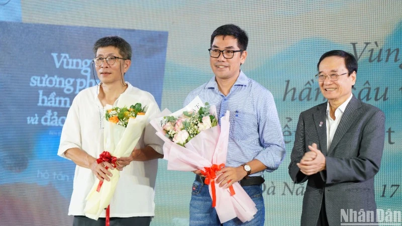 Ông Lương Minh Sâm, Chủ tịch Hội đồng Trường đại học Đông Á tặng hoa chúc mừng hai tác giả Trần Tuấn và Hồ Tấn Vũ. (Ảnh: ANH ĐÀO)