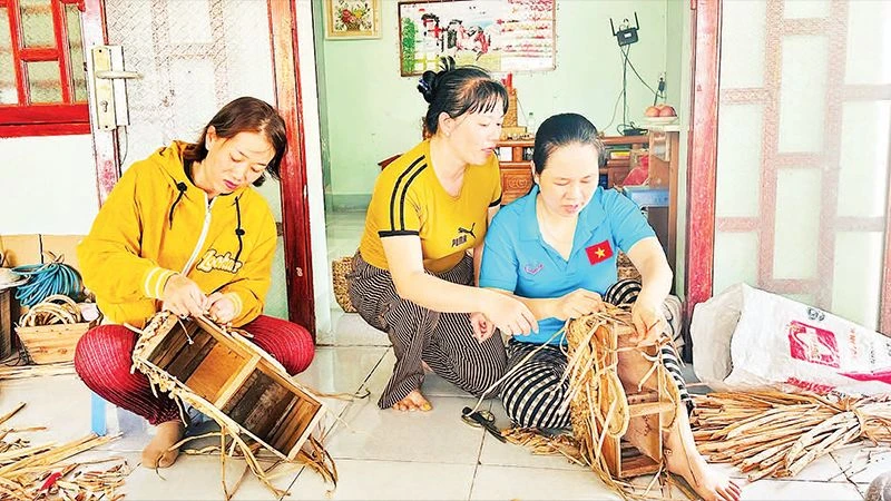 Chị em phụ nữ Tổ hợp tác đan lục bình Hồng Lan-Long Sơn hướng dẫn nhau đan các sản phẩm từ lục bình.