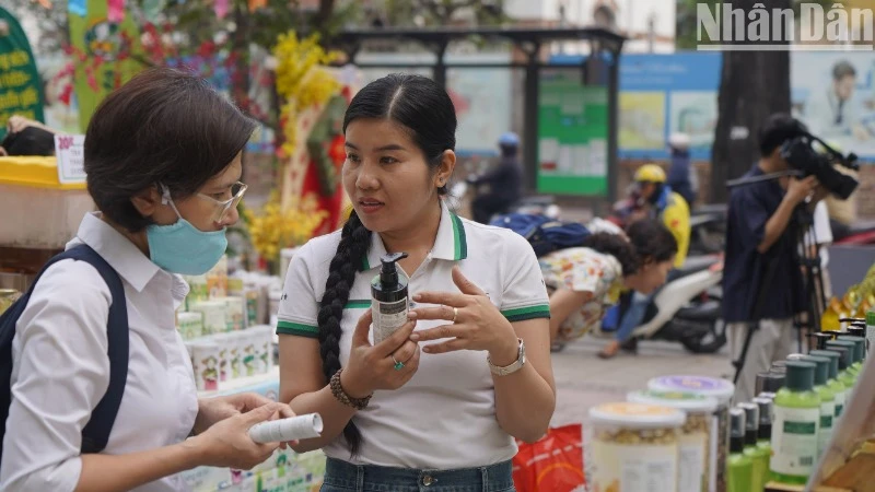 Người bán hàng giới thiệu những ưu điểm của sản phẩm cho khách hàng tại phiên chợ.