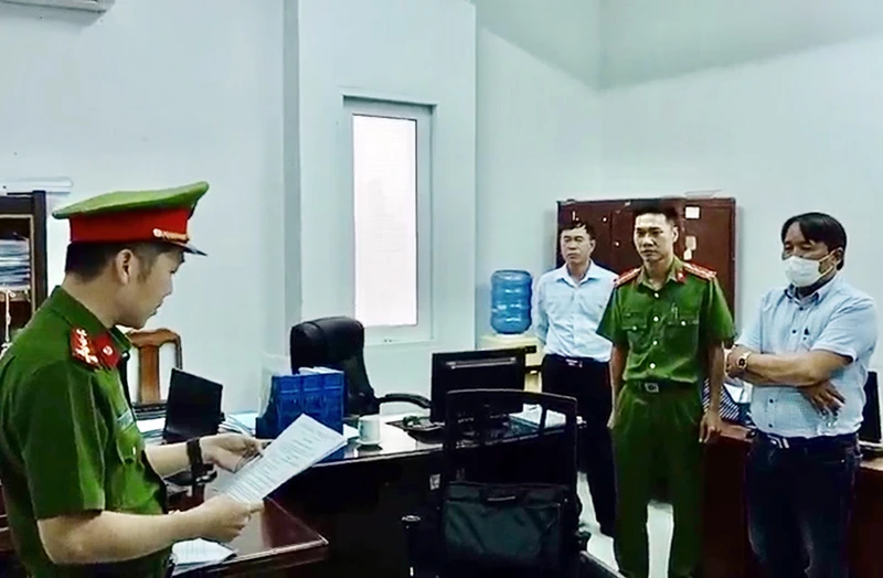 Trần Hữu Dũng (khoanh tay) nghe lệnh bắt bị can từ cơ quan chức năng.