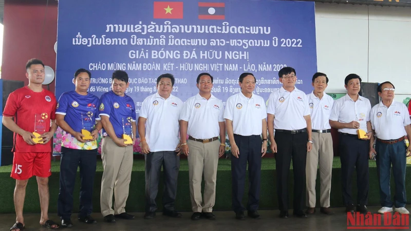 Bộ trưởng Giáo dục và Thể thao Lào Phouth Simmalavong và Đại sứ Nguyễn Bá Hùng chụp ảnh lưu niệm với đại diện các đội bóng. (Ảnh: TRỊNH DŨNG)