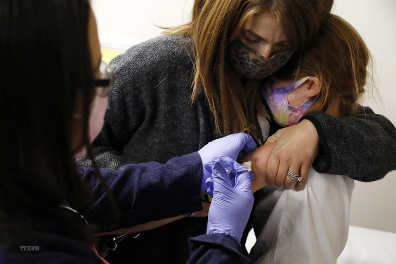 Nhân viên y tế tiêm vaccine ngừa Covid-19 cho trẻ em. (Ảnh: AFP/TTXVN)