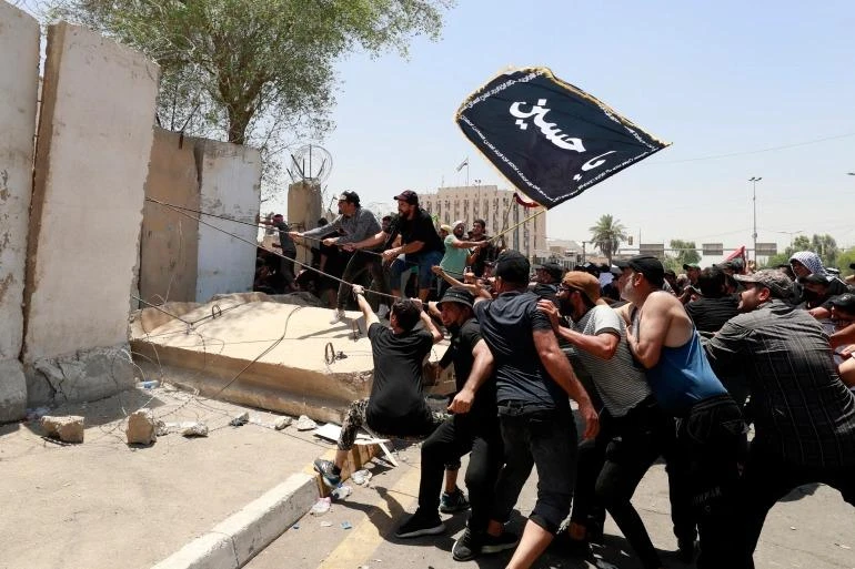 Người biểu tình kéo đổ 1 mảng tường bao quanh Vùng Xanh ở Baghdad. (Ảnh: Getty Images) 