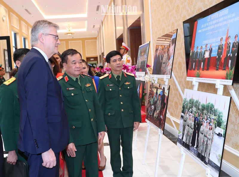 Thượng tướng Hoàng Xuân Chiến, Thứ trưởng Quốc phòng và Phó Tổng Thư ký Liên hợp quốc Jean-Pierre Lacroix cùng các đại biểu xem triển lãm ảnh về phụ nữ với hoạt động gìn giữ hòa bình Liên hợp quốc.