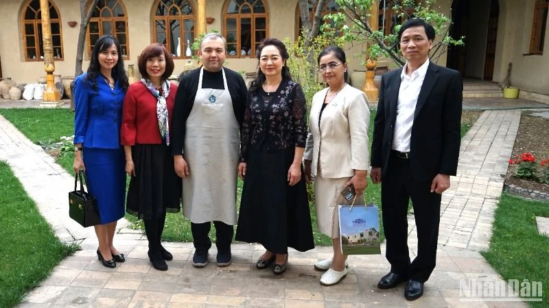Phu nhân Chủ tịch Quốc hội và các thành viên tháp tùng chụp ảnh kỷ niệm với chủ gia đình cơ sở trưng bày gốm truyền thống Uzbekistan.