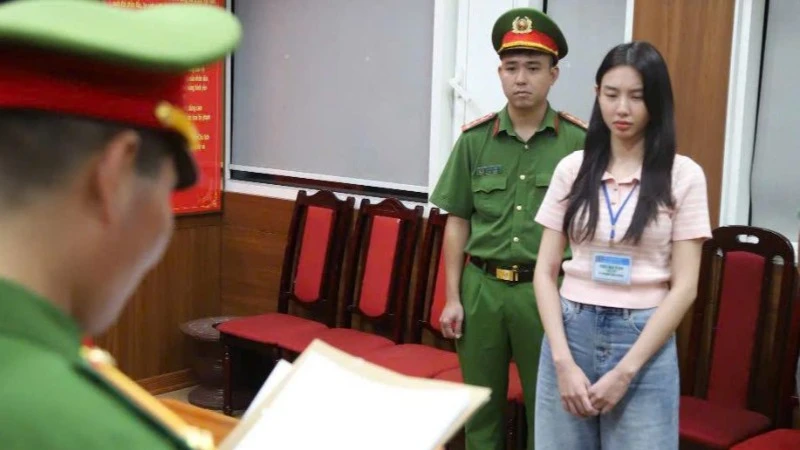 Hoa hậu Nguyễn Thúc Thùy Tiên nghe đọc lệnh từ cơ quan công an. (Ảnh: Bộ Công an) 