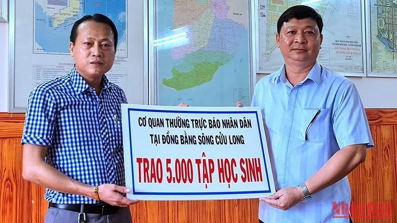 Chủ tịch Ủy ban nhân dân huyện Đầm Dơi (bìa phải) tiếp nhận 5.000 tập hỗ trợ từ Cơ quan Thường trực Báo Nhân Dân tại vùng đồng bằng sông Cửu Long.