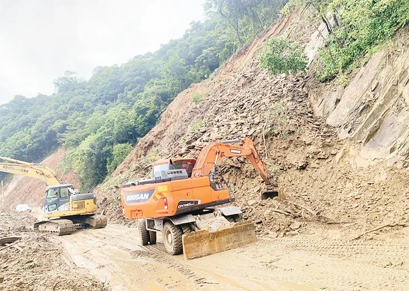 Các đơn vị huy động phương tiện thông tuyến quốc lộ 8A đoạn qua xã Sơn Kim 2, huyện Hương Sơn (Hà Tĩnh) sau khi bị mưa, lũ gây ách tắc.