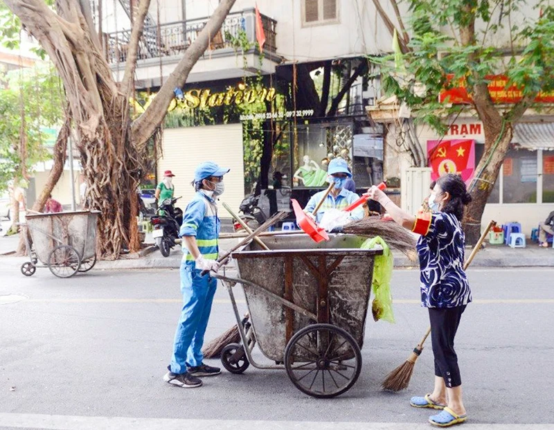 Công nhân Công ty Môi trường đô thị Hà Nội thường xuyên dọn vệ sinh các tuyến đường. (Ảnh PHẠM HÒA)