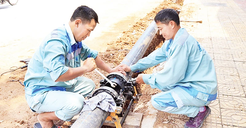 Thi công lắp đặt đường ống dẫn nước sạch tại huyện Đông Anh. (Ảnh NGUYỄN QUANG)