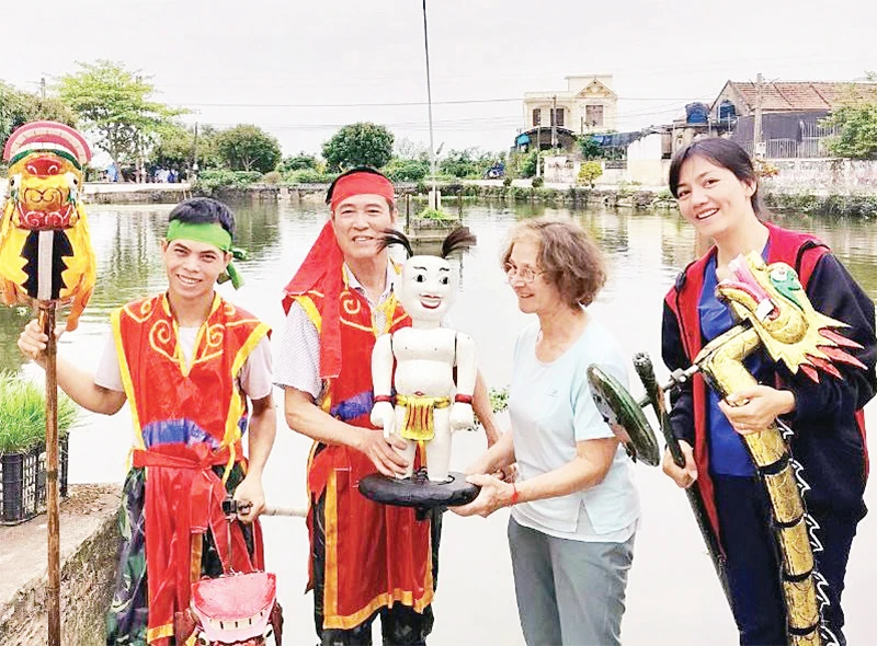 Du khách quốc tế trải nghiệm nghệ thuật rối nước truyền thống cùng các nghệ nhân-nông dân tại xã Hồng Quang, huyện Nam Trực (Nam Định). (Ảnh XUÂN KHÁNH) 