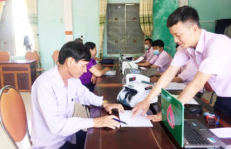 Cán bộ Ngân hàng Chính sách xã hội huyện Kỳ Anh hướng dẫn người dân làm thủ tục tại điểm giao dịch xã.