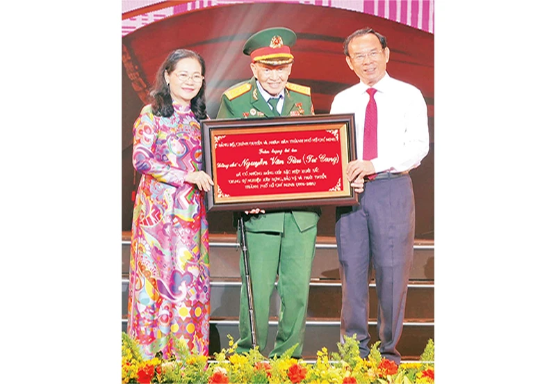Đồng chí Nguyễn Văn Nên, Ủy viên Bộ Chính trị; Bí thư Thành ủy Thành phố Hồ Chí Minh trao bảng tôn vinh Đại tá, Anh hùng Lực lượng Vũ trang nhân dân Nguyễn Văn Tàu (Tư Cang).