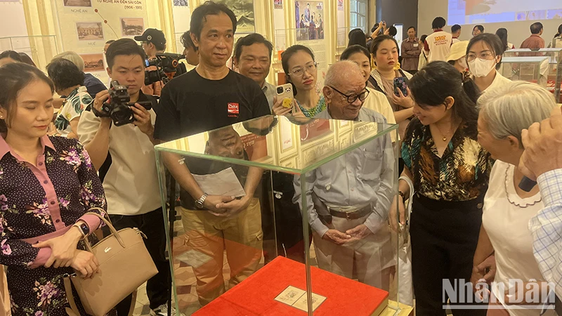 Khách tham quan thưởng lãm block tem kỷ niệm 70 năm Ngày sinh Chủ tịch Hồ Chí Minh có chữ ký của Người. (Ảnh: M.H)