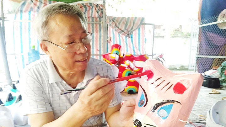 Ông Đông đang tô mầu và giới thiệu về chiếc mặt nạ trung thu.
