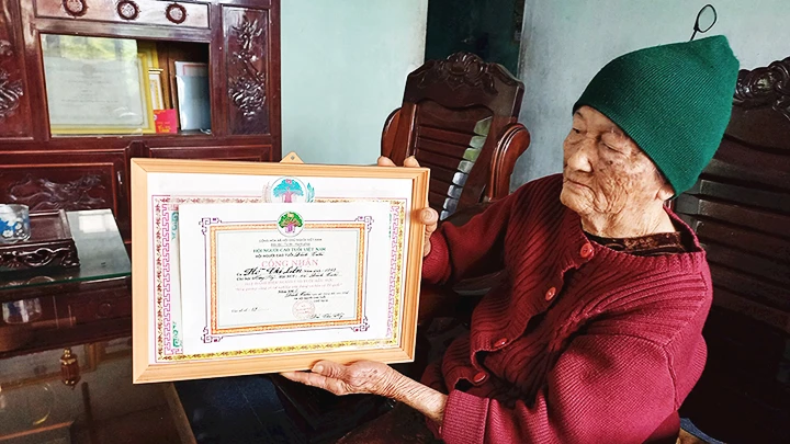 Bà Liên nâng niu tấm bằng công nhận thành tích người cao tuổi mẫu mực, nêu gương sáng vì sự nghiệp xây dựng và bảo vệ Tổ quốc.