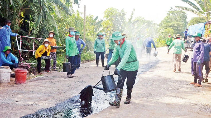 Các thành viên của Đội vá đường thiện nguyện huyện Chợ Mới đổ nhựa đường, thi công đoạn đường nông thôn xuống cấp.