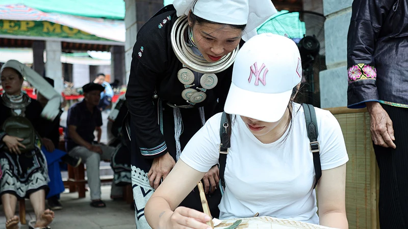 Nghệ nhân hướng dẫn du khách in sáp ong.