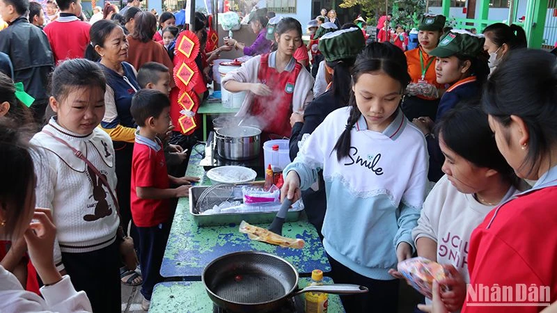 Các em học sinh hào hứng trải nghiệm và thưởng thức những món ăn truyền thống của Việt Nam tại hội chợ. (Ảnh: Hải Tiến)