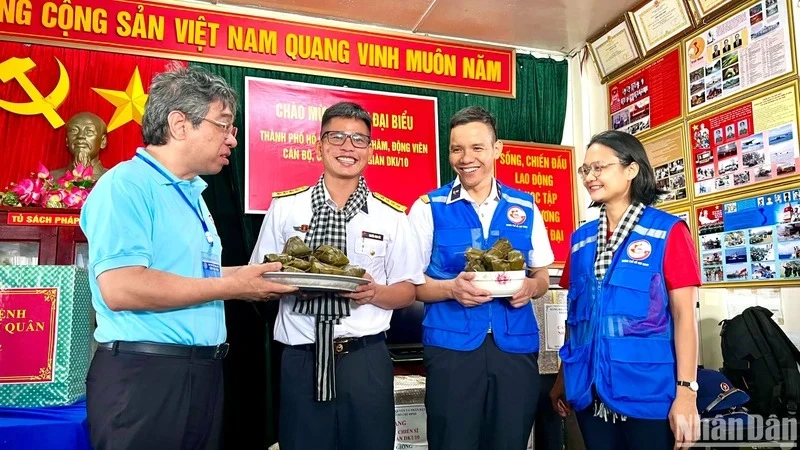 Đồng chí Nguyễn Phước Lộc, Phó Bí thư Thành ủy, Chủ tịch Ủy ban Mặt trận Tổ quốc Việt Nam Thành phố Hồ Chí Minh (bên trái) trao bánh giò mới nấu đến cán bộ, chiến sĩ trên nhà giàn DK1/10.