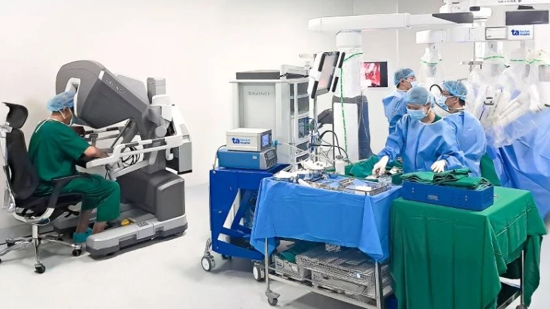 Phó Giáo sư, Tiến sĩ Vũ Lê Chuyên (trái) đang ngồi ở buồng điều khiển robot Da Vinci Xi để phẫu thuật cho người bệnh.