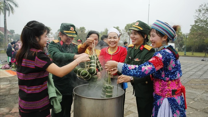 Đồng bào các dân tộc đang hoạt động tại "Làng" cùng các chiến sĩ tham gia luộc bánh chưng. (Ảnh: PH)