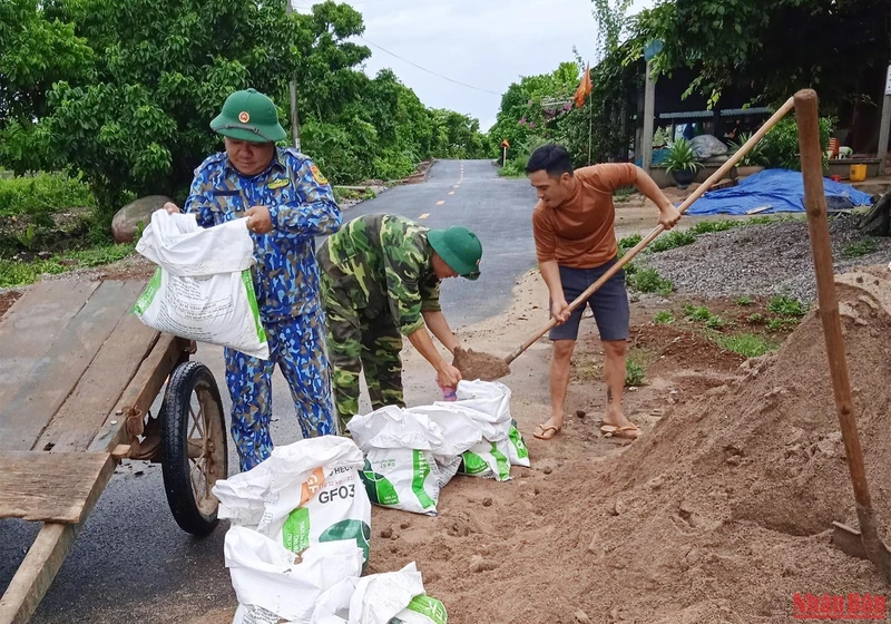 Bộ đội Biên phòng Đảo Cồn cỏ và các lực lượng chức năng giúp người dân tải cát chằng chống mái nhà.