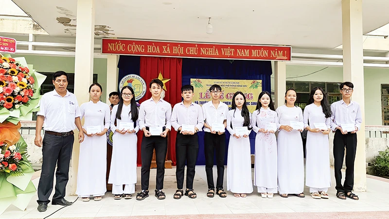 Thầy Trịnh Thanh Thu (bìa trái) trao hỗ trợ cho học sinh. (Ảnh Trường THPT Nông Sơn)