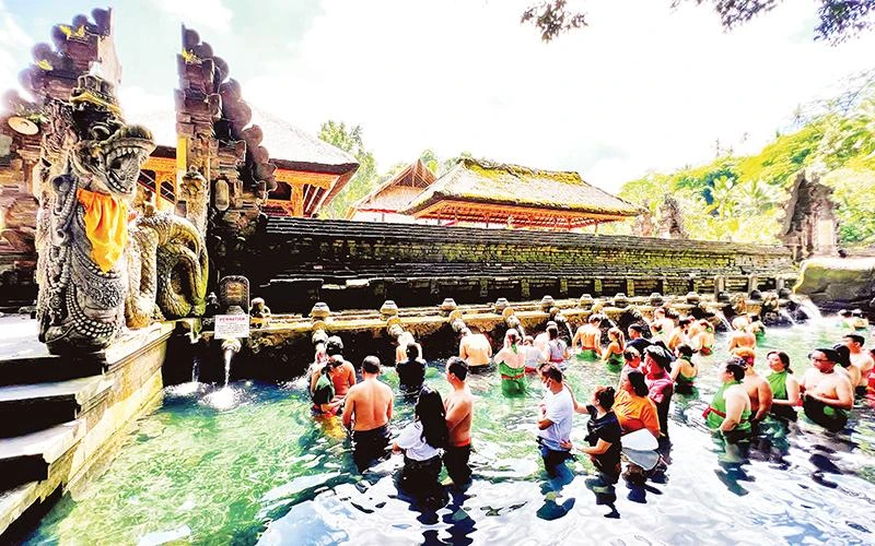 Người dân và du khách xếp hàng chờ đến lượt thực hiện nghi thức tắm nước suối thiêng ở đền Tirta Empul.