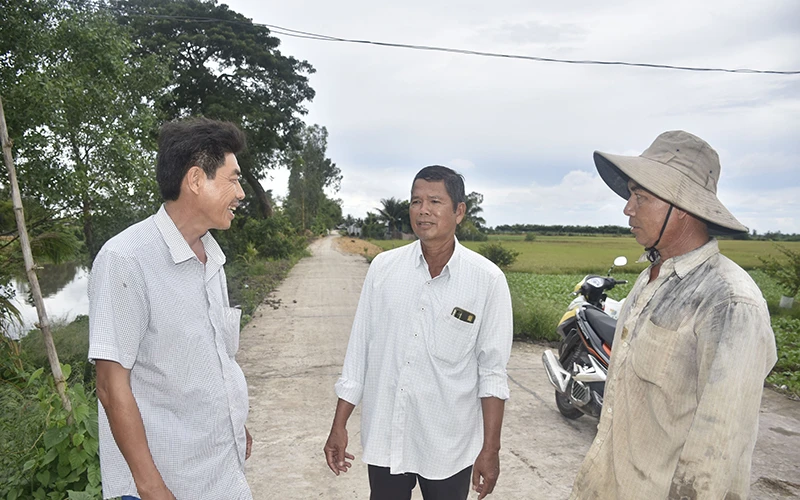 Ông Lương Văn Tạo (ở giữa), Bí thư Chi bộ, Trưởng ấp Sóc Cung tuyên truyền cho người dân về ý nghĩa của việc hiến đất làm đường giao thông nông thôn.
