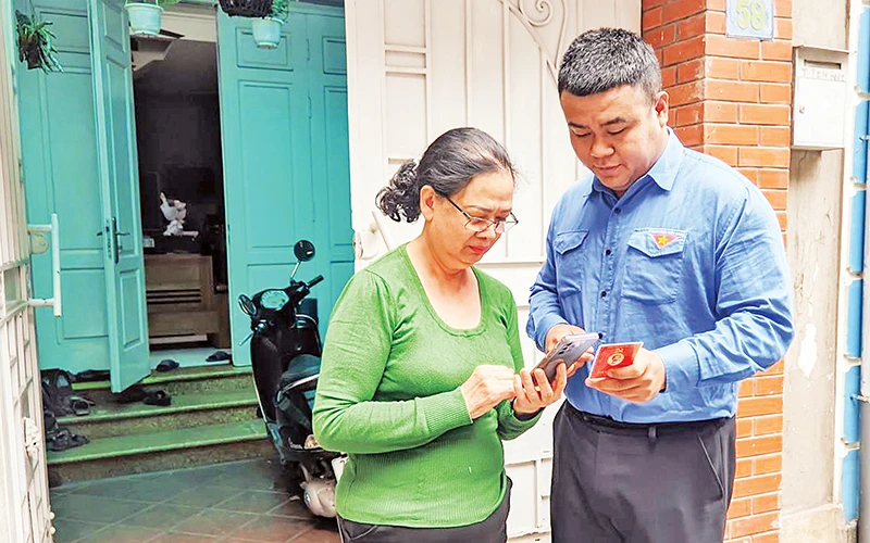 Đoàn viên thanh niên phường Thụy Khuê (Tây Hồ) hướng dẫn sử dụng ứng dụng “Sổ tay đảng viên điện tử Thành ủy Hà Nội”. (Ảnh VIẾT TUẤN)