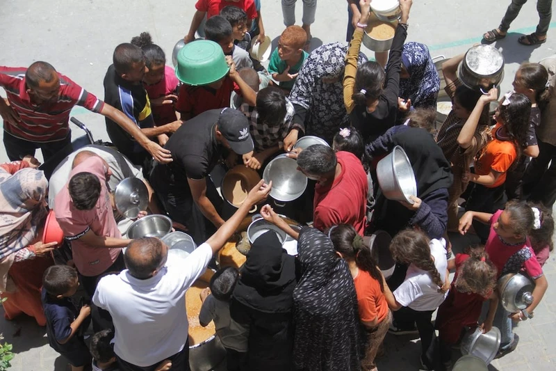 Người dân Palestin nhận đồ ăn từ thiện. Ảnh: Reuters
