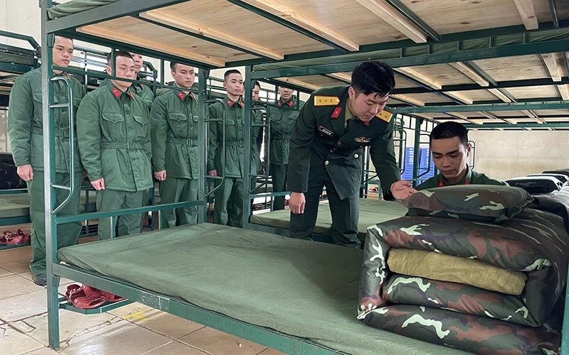 Chỉ huy Đại đội 8, Tiểu đoàn 2, Trung đoàn 2, Sư đoàn 395 (Quân khu 3) hướng dẫn chiến sĩ mới cách gấp chăn, màn. (Ảnh: Nguyên Trường)