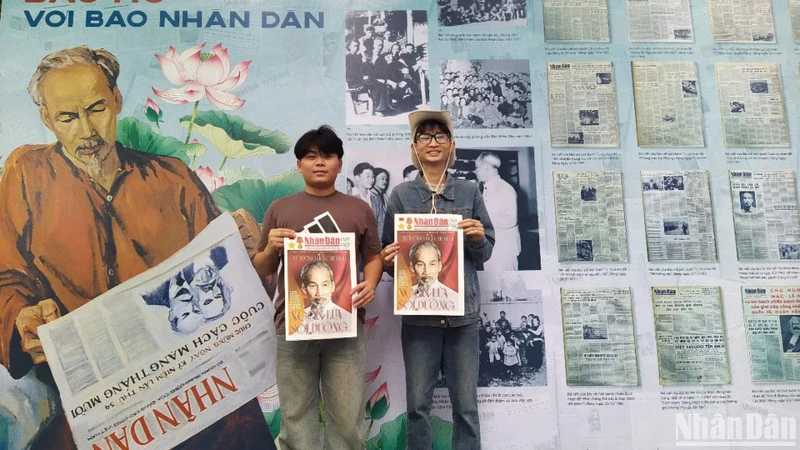 Bạn Nguyễn Đức Tân (đeo kính), sinh viên trường Cao đẳng Du lịch Hà Nội cùng bạn rất vui khi được cầm trên tay tờ báo Nhân Dân cuối tuần số đặc biệt chụp ảnh lưu niệm. (ẢNH: KIM CƯƠNG)