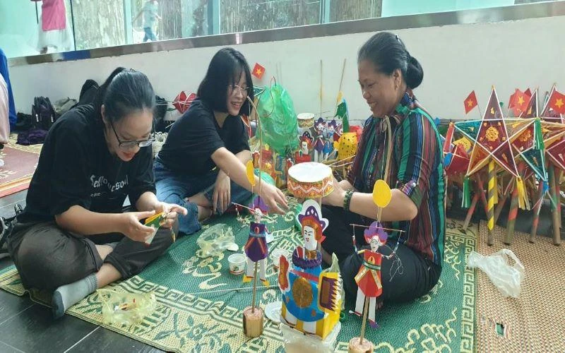 Nghệ nhân Nguyễn Thị Tuyến đang hướng dẫn cách làm đồ chơi trung thu cho du khách.
