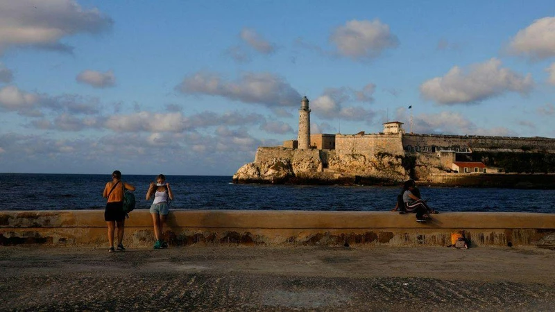 Du khách đeo khẩu trang sau khi chụp ảnh tại đại lộ El Malecon ven biển, ngày 7/2/2022. (Ảnh: Reuters)