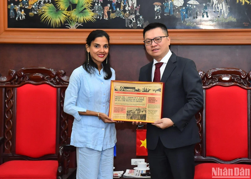 Tổng Biên tập Báo Nhân Dân Lê Quốc Minh nhận quà lưu niệm của Phó Tổng Biên tập Báo Granma Arlin Alberty Loforte. (Ảnh: THỦY NGUYÊN)