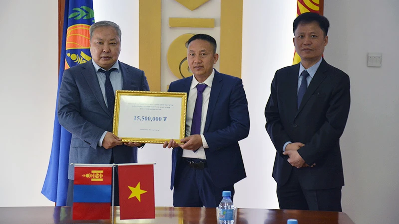 Ông Phạm Quyết Tiến, đại diện cộng đồng người Việt Nam tại Mông Cổ trao khoản tiền quyên góp cho Tổng Cục trưởng NEMA Mông Cổ G.Ariunbuyan trước sự chứng kiến của Đại sứ Việt Nam tại Mông Cổ Doãn Khánh Tâm. (Ảnh: Đại sứ quán Việt Nam tại Mông Cổ)