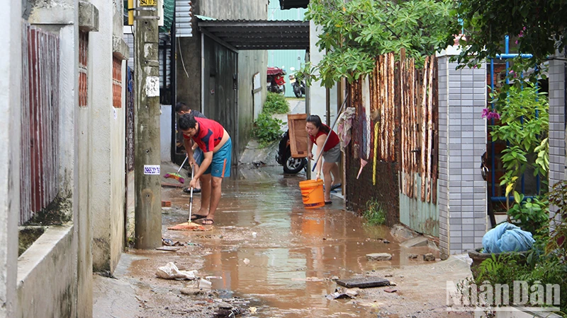 Người dân dọn dẹp bùn đất sau trận lụt.