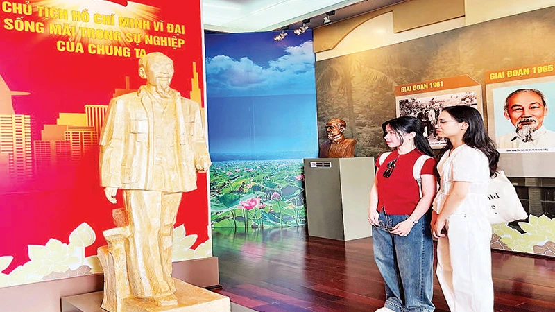Bạn trẻ thưởng lãm tác phẩm “Bác Hồ về thăm quê hương Nghệ An lần thứ hai” của tác giả Nguyễn Xuân Tiên. (Ảnh MẠNH HẢO).
