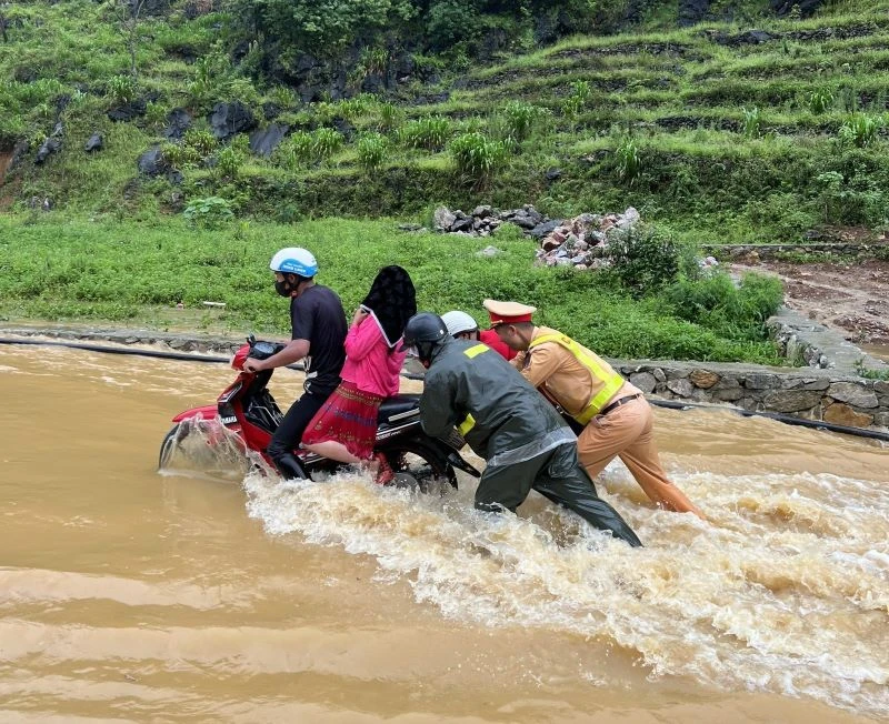Cảnh sát giao thông Hà Giang lội nước đẩy xe máy, đưa người dân qua điểm ngập an toàn.