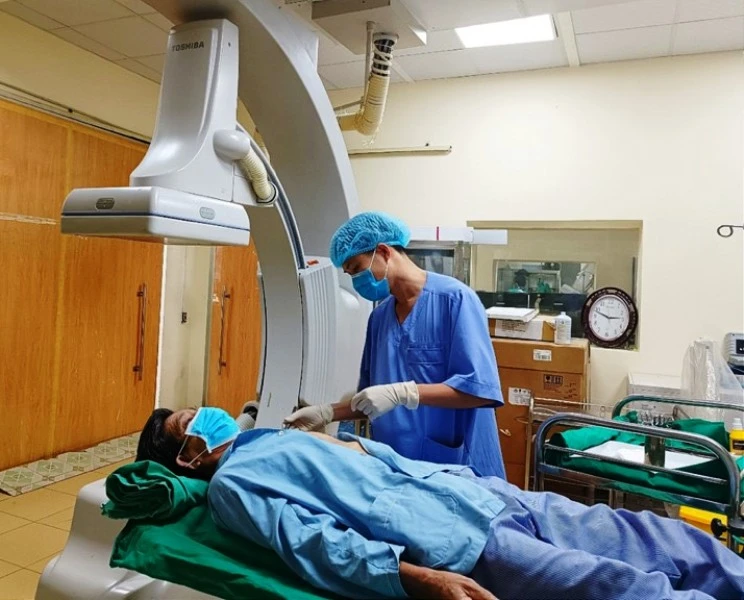 Nhân viên y tế sử dụng thiết bị hiện đại kiểm tra sức khỏe bệnh nhân sau can thiệp tim mạch.