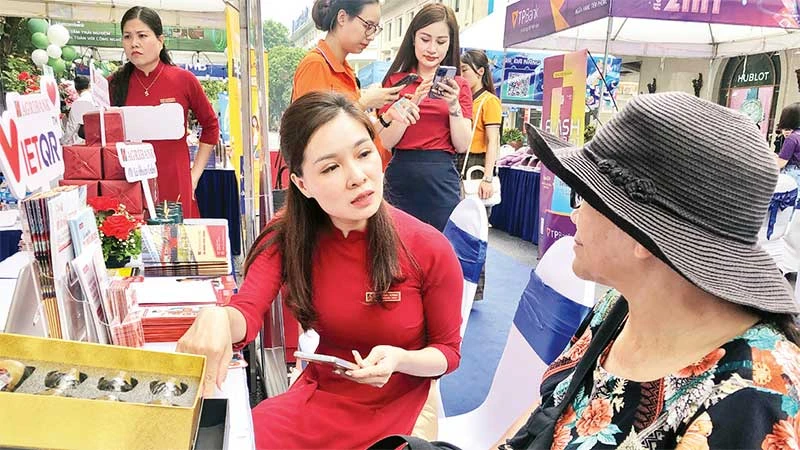 Cán bộ ngân hàng hướng dẫn người dân cách thanh toán không dùng tiền mặt.