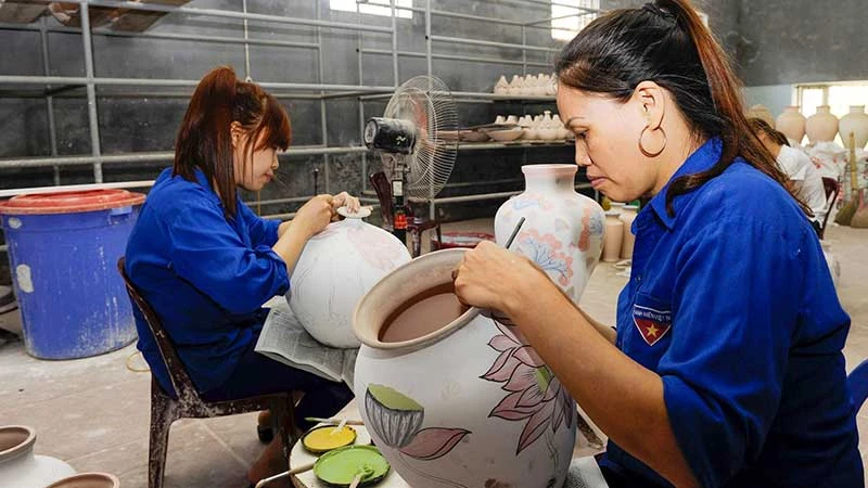 Vẽ hoa văn lên sản phẩm tại làng gốm Bát Tràng, Hà Nội. (Ảnh TUỆ NGHI)