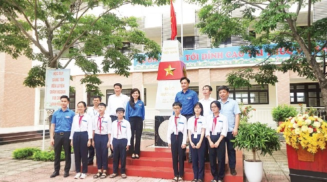 Đại biểu và các em học sinh chụp ảnh lưu niệm với Cột mốc chủ quyền biển đảo.