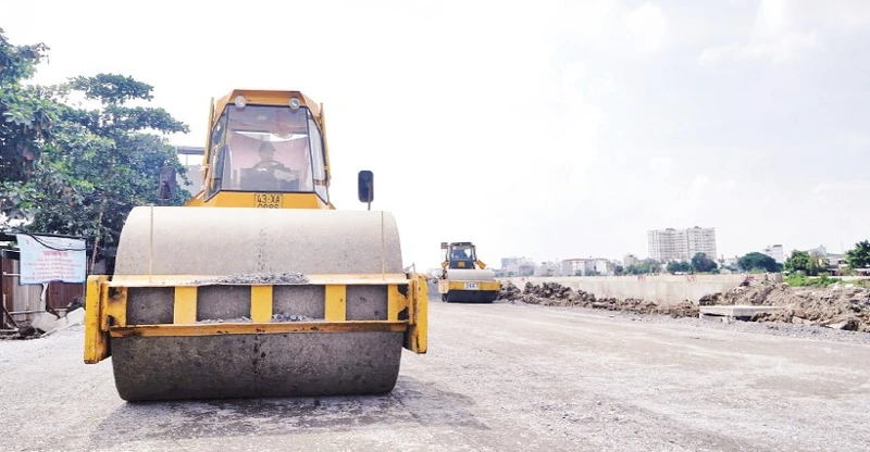 Thi công trải nhựa đường ven kênh Tham Lương, đoạn qua cầu Bến Phân đến cầu An Lộc trên địa bàn Quận 12, Thành phố Hồ Chí Minh. (Ảnh THẾ ANH)