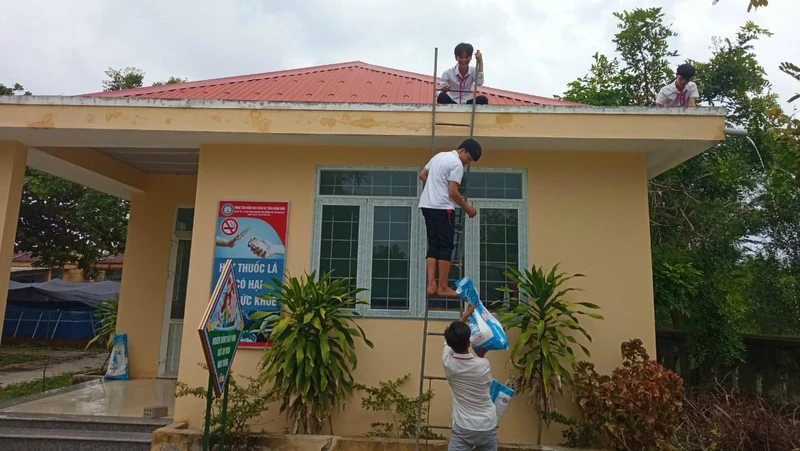 Học sinh tại Quảng Bình tham gia chèn mái tôn trường học để hạn chế thiệt hại do gió bão. 