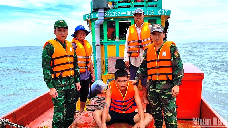 Nạn nhân Minh (ngồi) bị trôi dạt trên biển được Bộ đội Biên phòng Cà Mau cứu vớt đưa vào bờ an toàn. 
