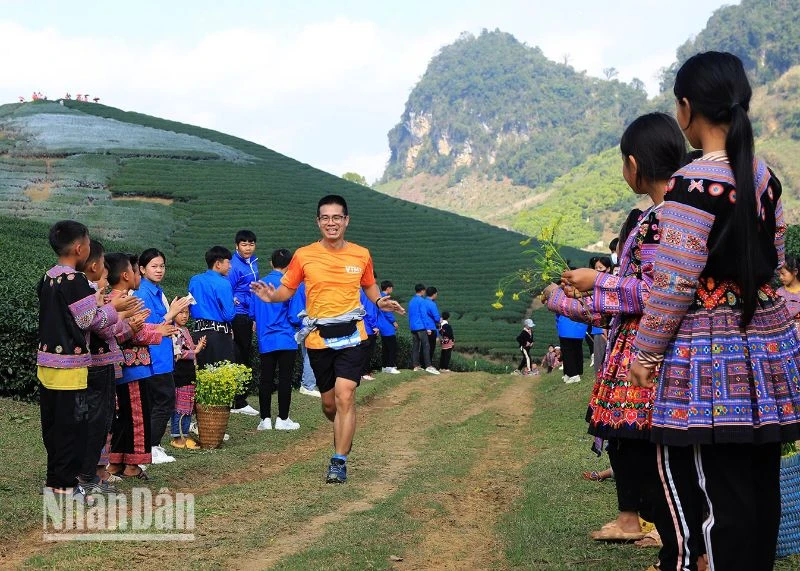 Học sinh dân tộc H'Mông đứng hai bên đường cổ động và tặng hoa cho các vận động viên.